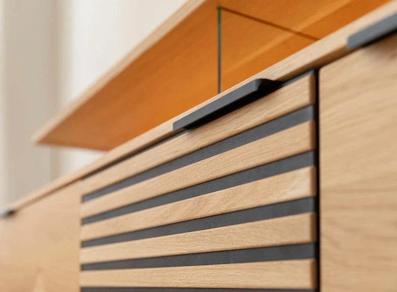 Beleuchtete Hängekommode aus massiver Eiche mit Lamellen | TV-Board Tirano II mit Schaukasten und grober Holzstruktur
