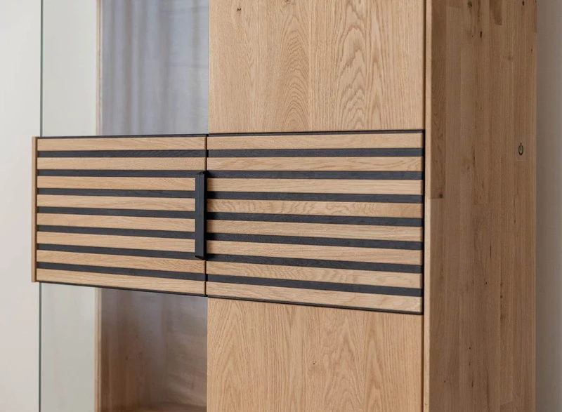 Beleuchtete Standvitrine aus massiver Eiche mit Lamellen | Wohnzimmerschrank Tirano II mit Rückwand in grober Holzstruktur