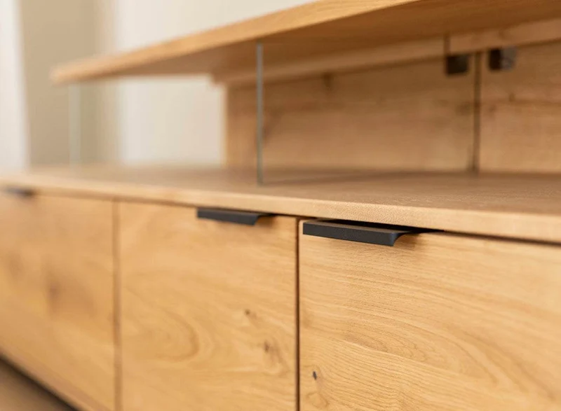 Beleuchtete Hängekommode aus massiver Eiche | TV-Board Tirano I mit Schaukasten und grober Holzstruktur